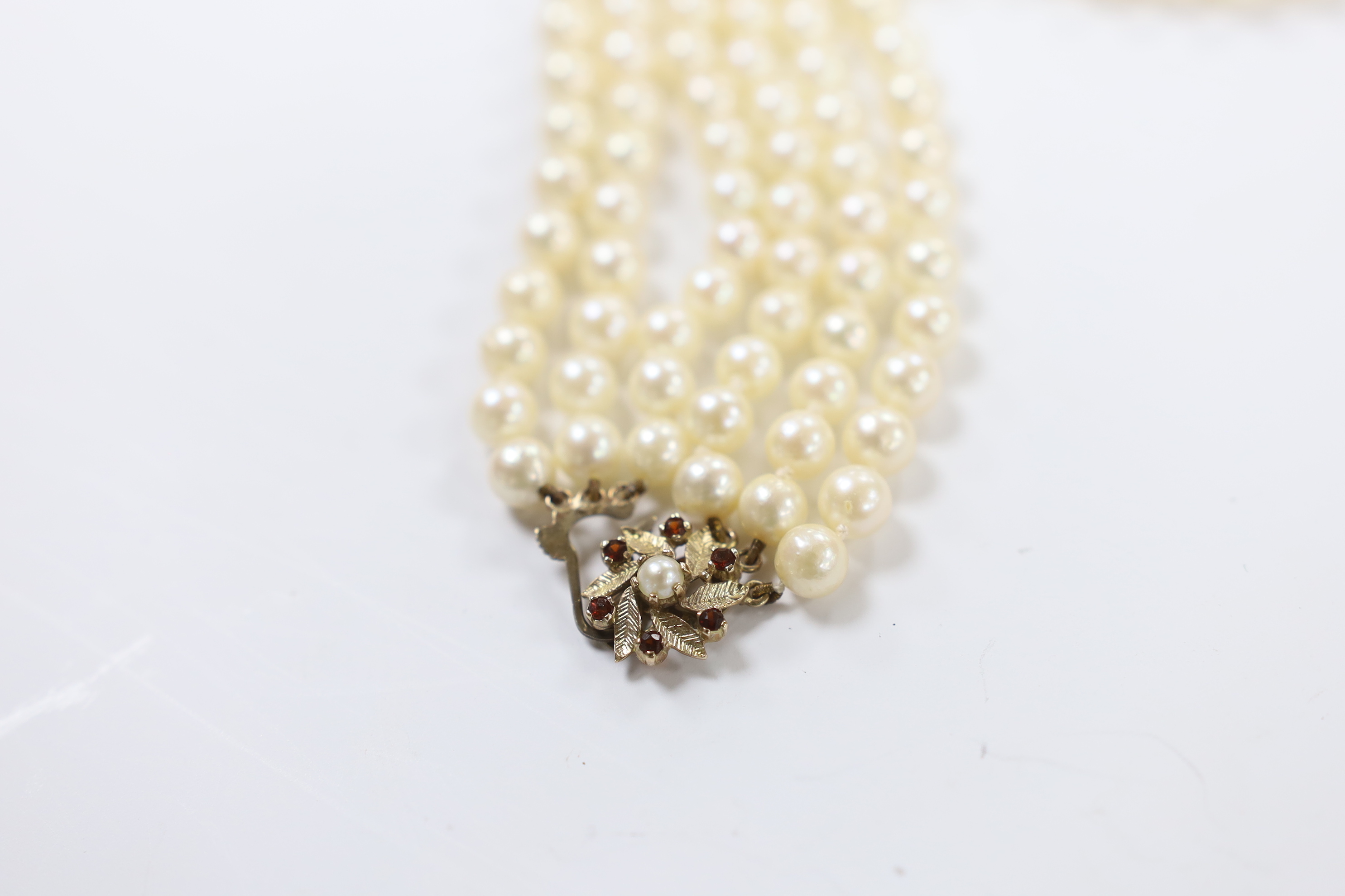 A triple strand cultured pearl choker necklace, with cultured pearl and garnet cluster set 9ct gold clasp, 36cm.